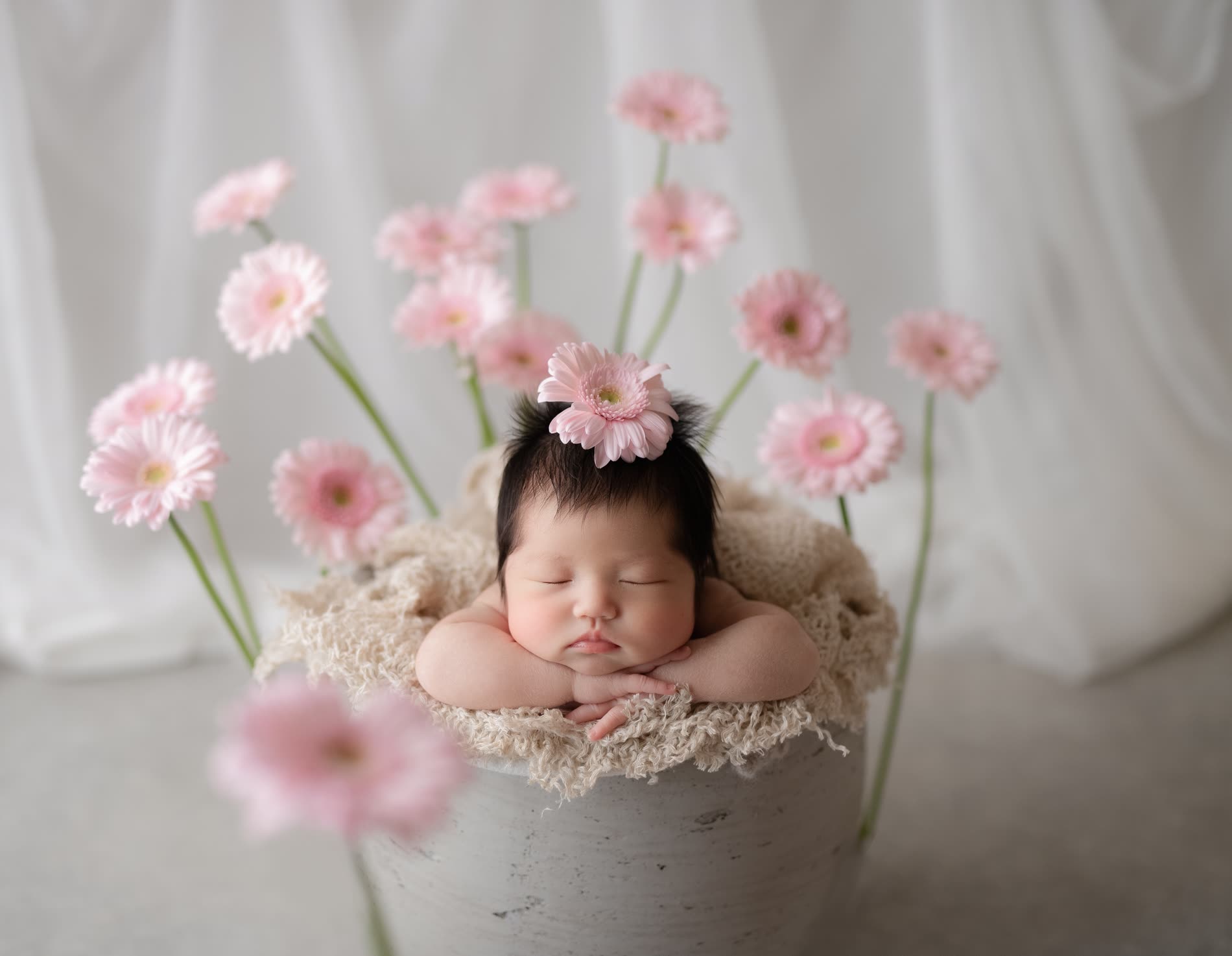 淡いピンクの生花に囲まれて眠る赤ちゃん