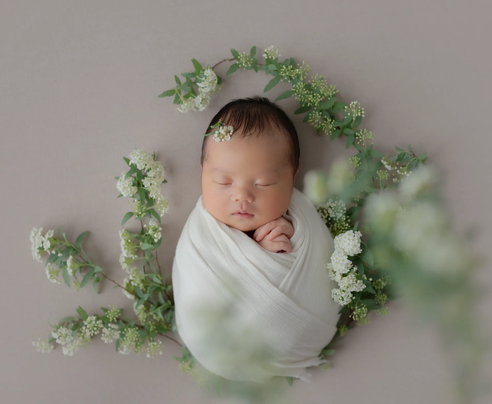 ユーカリと白い花に囲まれて眠る赤ちゃん