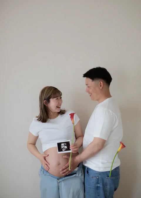 エコー写真とカラーの花を手に見つめ合うご夫婦のマタニティフォト